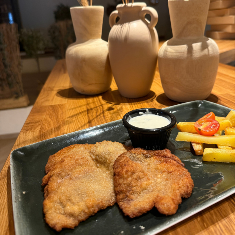 Plato rebozado acompañado de patatas y salsa en Di Manuella.