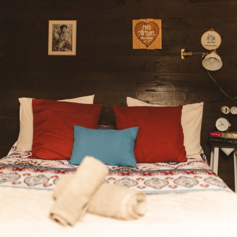 Cama de un alojamiento rural de La Vallicuerra con cojines y toallas preparadas.