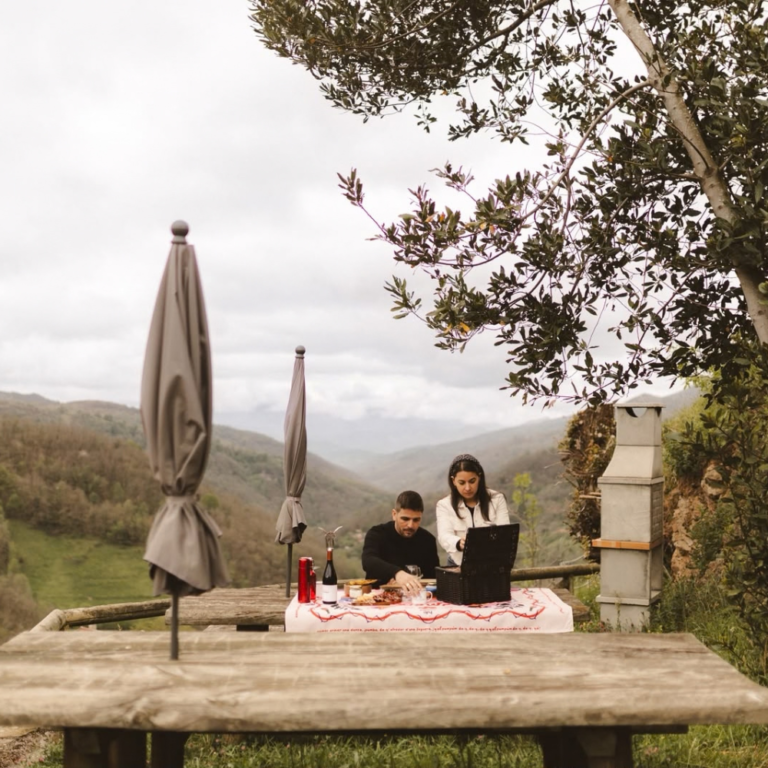 Una pareja junto a una mesa exterior con vistas al valle en La Vallicuerra.